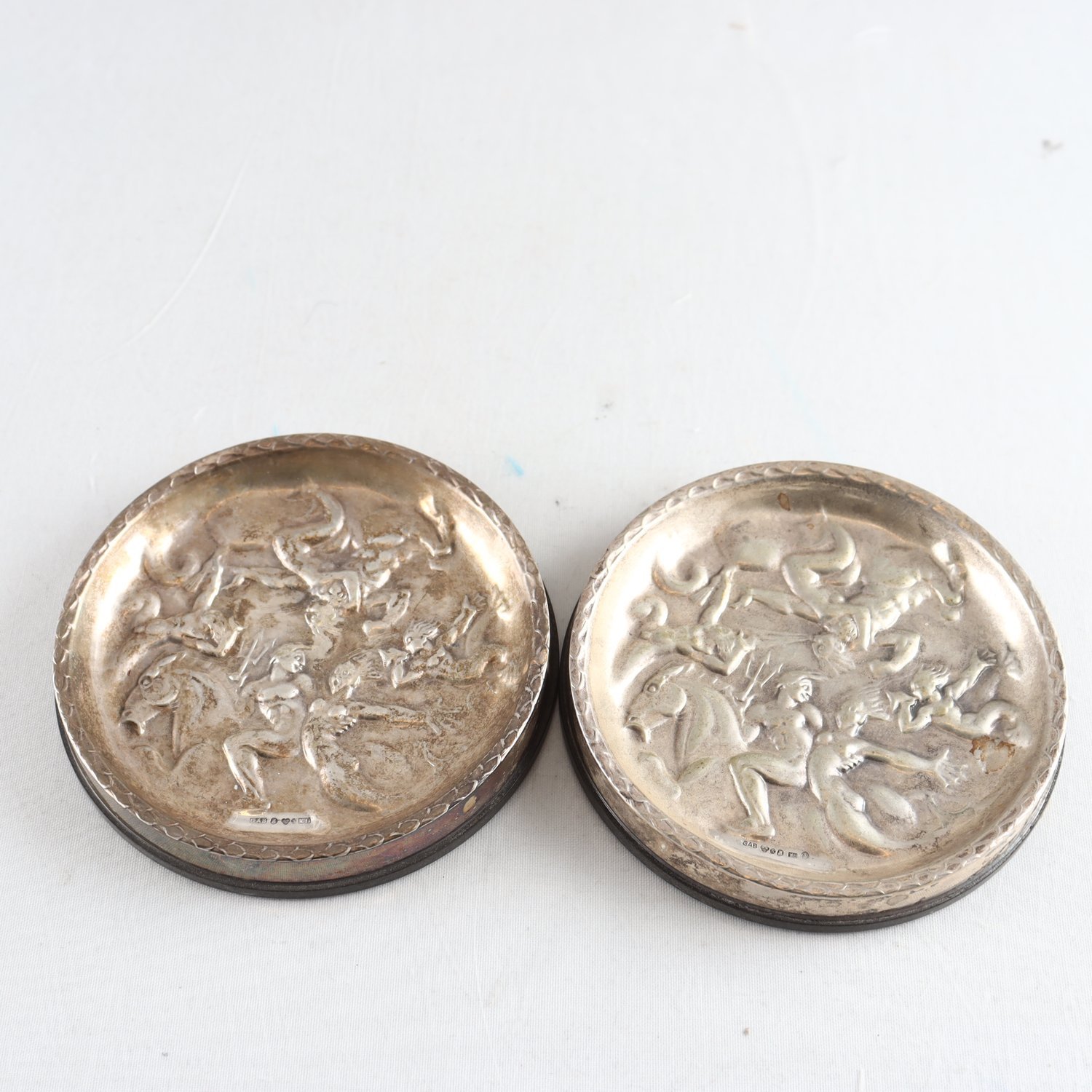 Coasters, silver, bakelit, Vindarnas lek, efter Carl Milles, GAB, 2 st