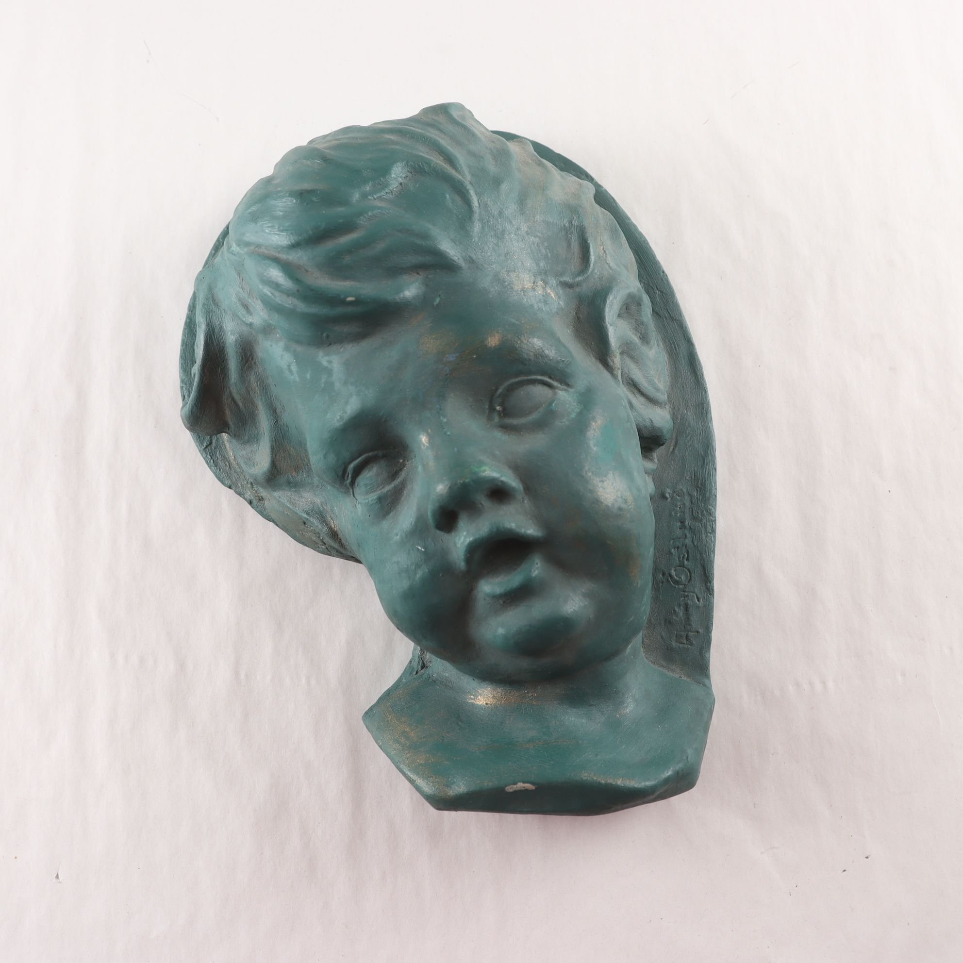 Relief, grönpatinerad gips, barnhuvud. Samfraktas ej